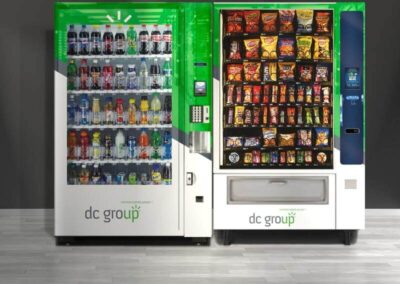 Green-and-white vending machine pair for DC Group with snack and beverage products